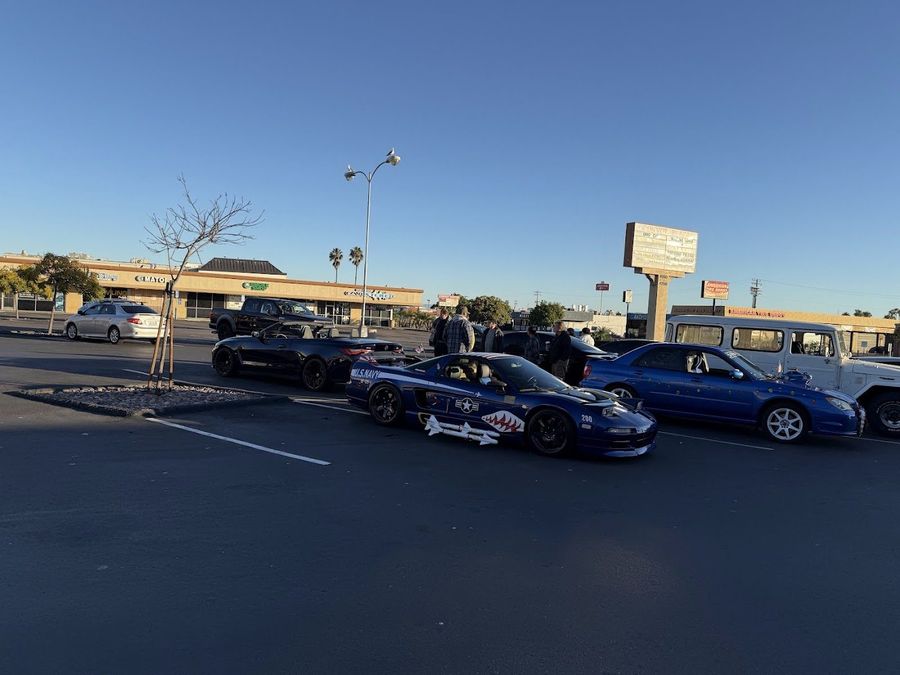 Blue sports cars lined up in the Pet Zone parking lot at sunrise