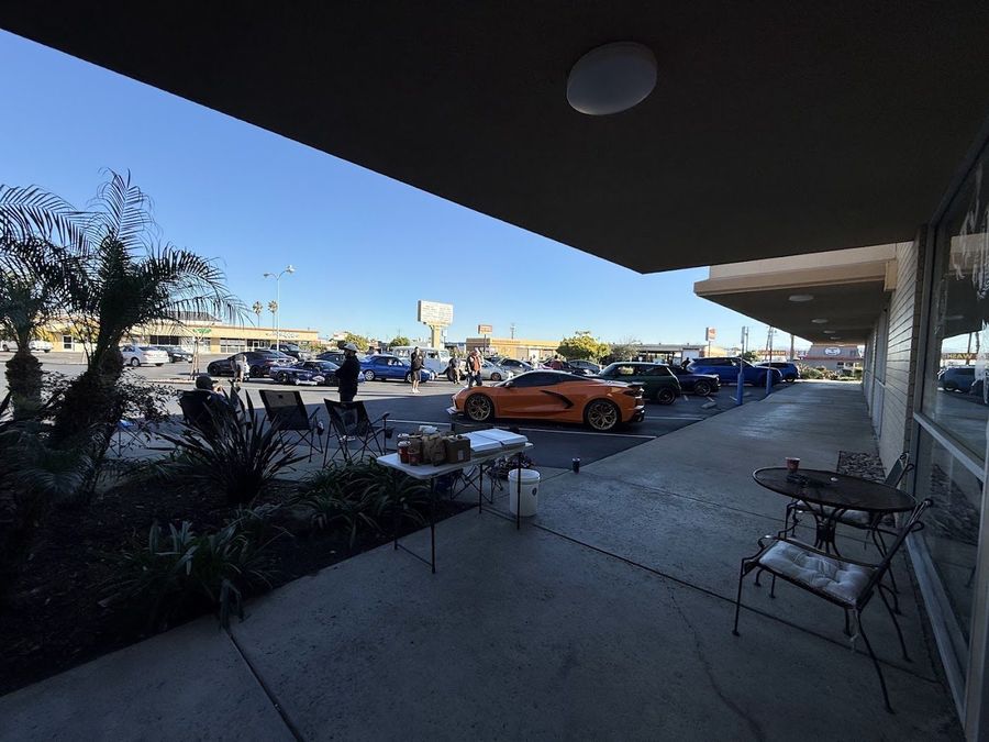 Coffee table and lounge chairs on the Pet Zone patio with an orange Corvette parked nearby